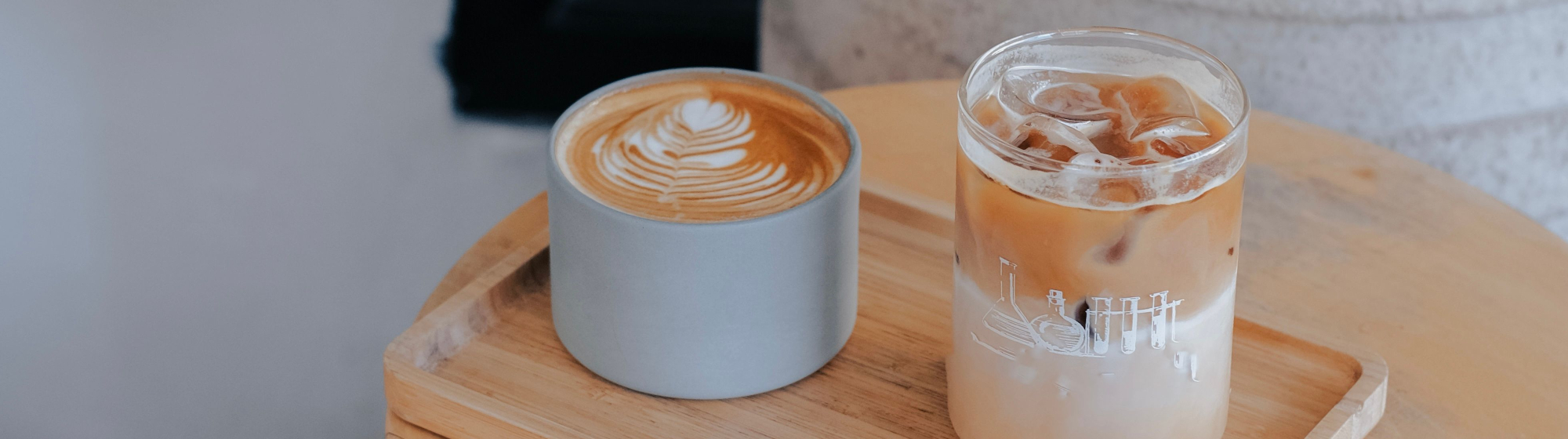 Cappuccino i grå keramikkopp och islatte i glas Cappuccino i grå keramikkopp bredvid islatte i klart glas