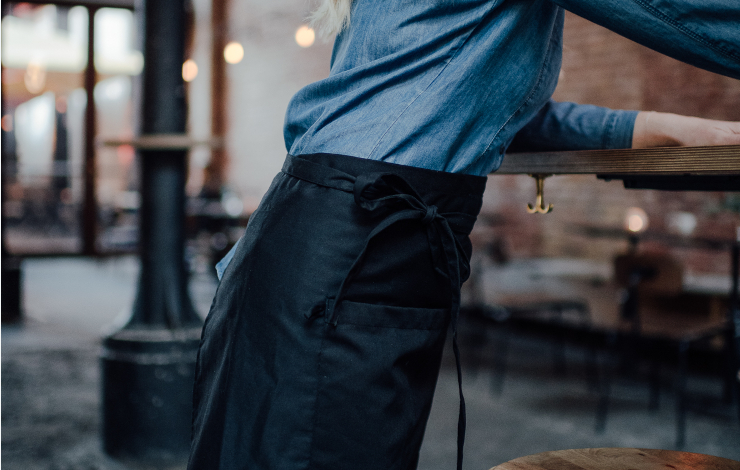 Servitör med svart midjeförkläde och jeansskjorta