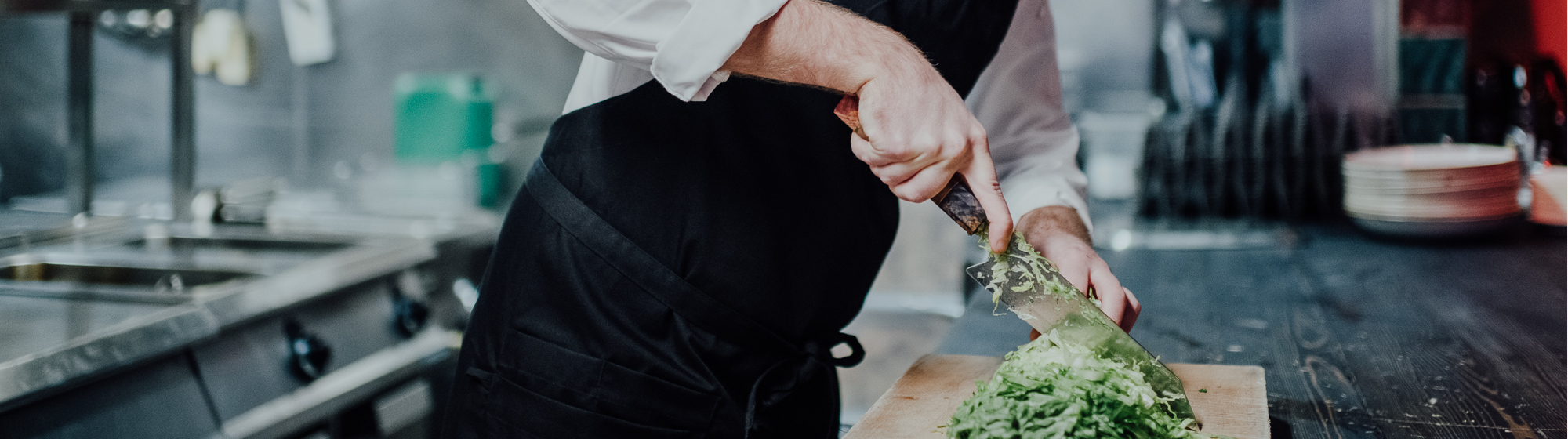 Kock i kök som skär färsk sallad Restaurangkök med en kock som skär sallad