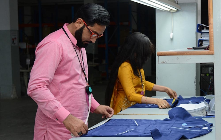 Två personer står och mäter kläder.