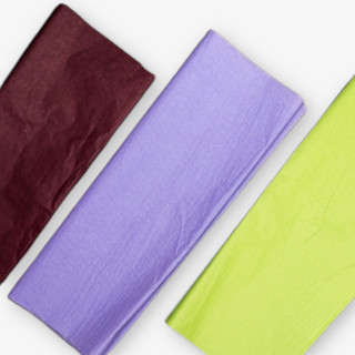 Tre färgglada silkespapper i vinrött, lila och limegrön ligger på en vit yta, vilket framhäver deras textur och färgkombination.