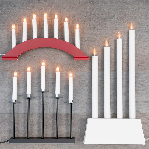 tre ljusstakar i rött, svart och vit upplagda på ett bord