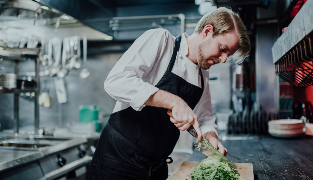 Kock i restaurangkök med kockkläder