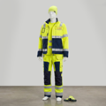 Godkända varselkläder (High-Vis) som kombinerar säkerhet med marknadsföring. Dockan visar ett komplett ställ med varseljacka och byxor i fluorescerande gult och marint, tryckta med företagsnamn på rygg och bröst. Nödvändigt för arbete vid väg och entreprenad där synlighet är lagkrav.