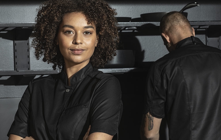 En kvinnlig kock i en svart kockrock.