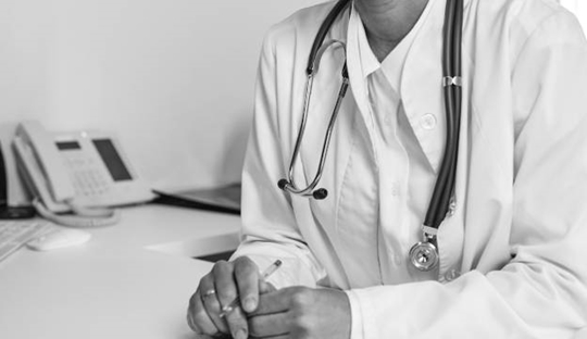 Läkare som arbetar vid sitt skrivbord på vårdklinik