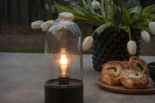 Bordslykta stående på ett bord med blommor och bullar